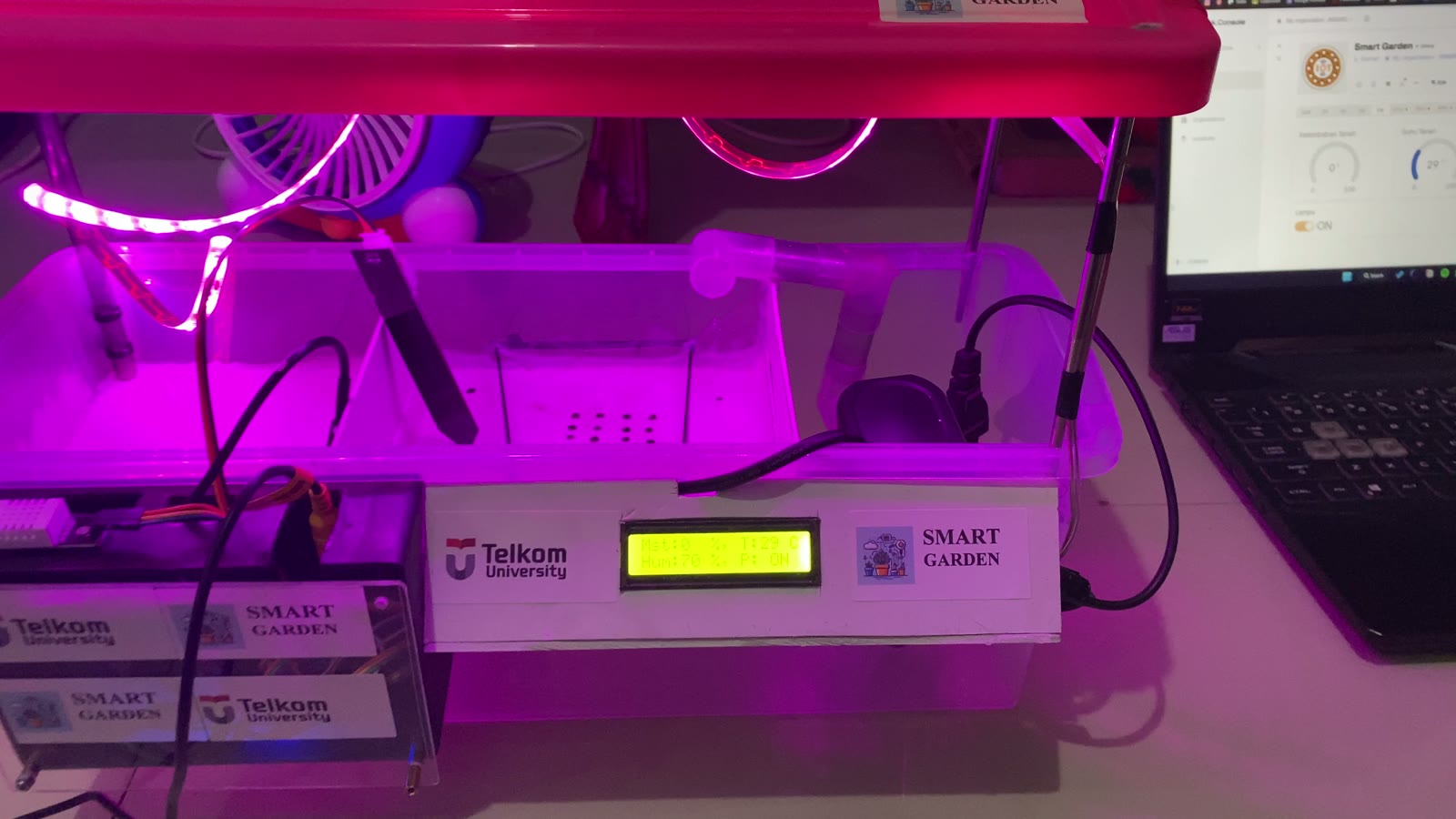 Alat Smart Garden Telkom University dengan lampu tanam ungu, sensor kelembapan tanah, dan layar LCD